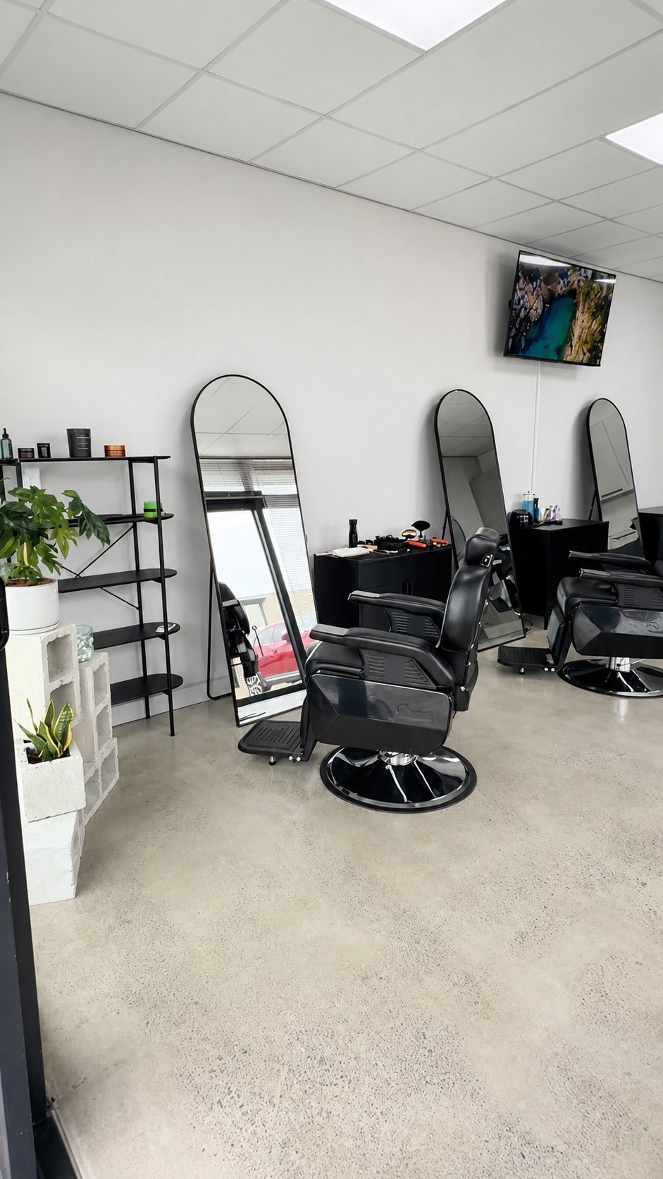 Black barber chairs and arched mirrors along a bright wall