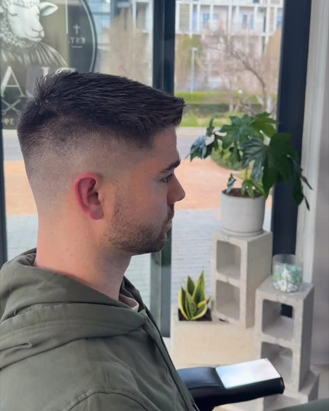 Side view of a textured top and blended fade on an adult client inside a barbershop